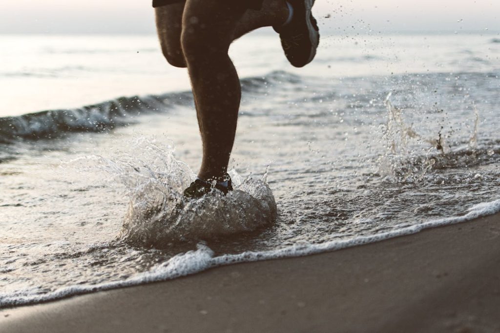 Dynamic shot of legs running on Palanga beach during sunrise, splashing water.